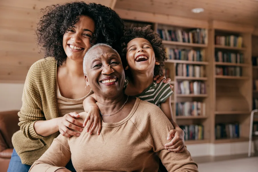 Família de três gerações abraçada e sorrindo